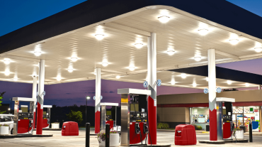 Moderne, beleuchtete Tankstelle in der Dämmerung mit mehreren Zapfsäulen und überdachter Fahrbahn – Symbolbild für zeitgemäßen Tankstellenbetrieb und 24/7-Verfügbarkeit.