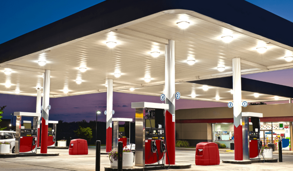 Moderne, beleuchtete Tankstelle in der Dämmerung mit mehreren Zapfsäulen und überdachter Fahrbahn – Symbolbild für zeitgemäßen Tankstellenbetrieb und 24/7-Verfügbarkeit.
