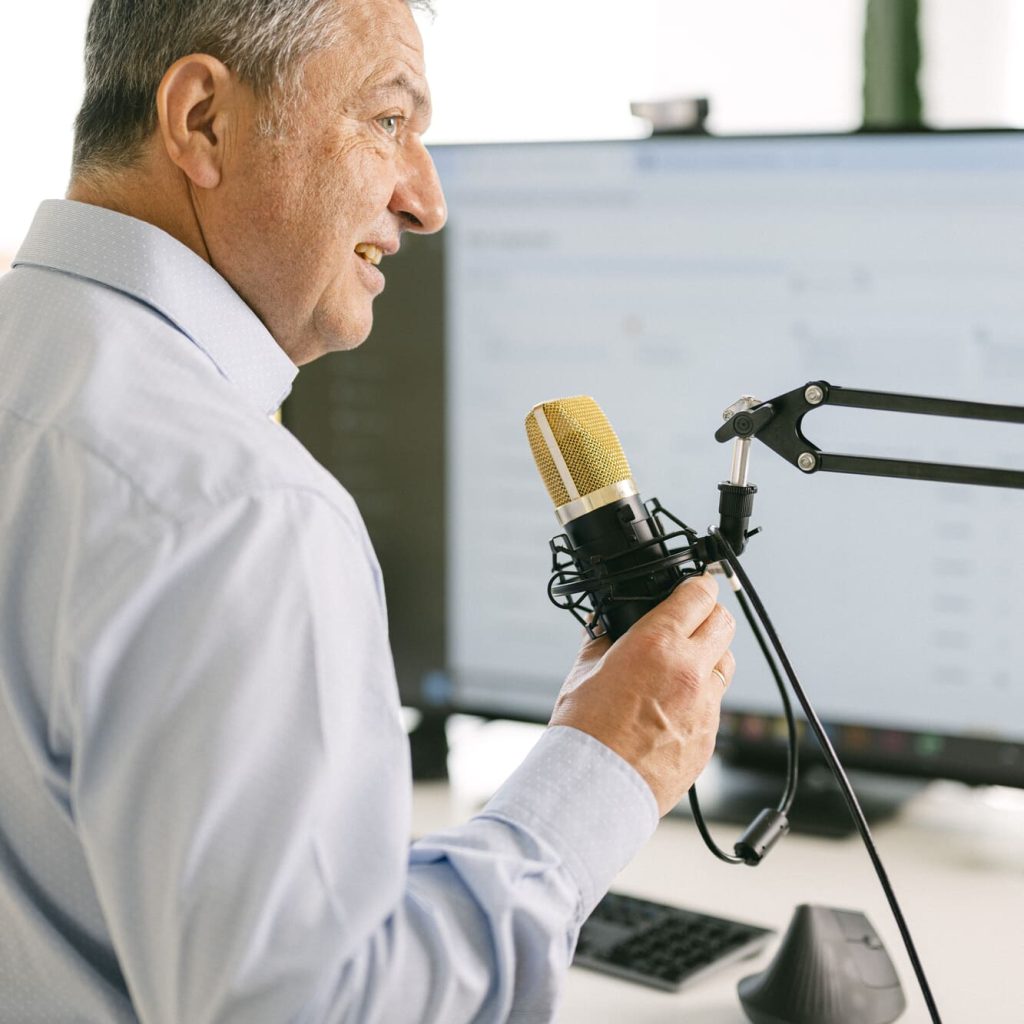 Mann mit Mikrofon spricht vor einem Bildschirm während einer Live-Demo der omis Software